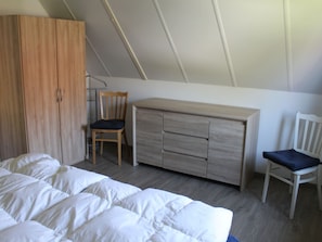 A bedroom with a bed, a wooden wardrobe, a desk, and two chairs. - Beautiful Holiday Home on the Beach (Breskens)