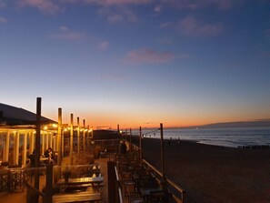 An outdoor seating area with tables and chairs, overlooking a beach and the ocean. - Beautiful Holiday Home on the Beach (Breskens)