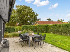 An outdoor patio with a table and chairs, surrounded by a well-maintained hedge and a lawn. - "Ellanor" - 100m from the sea by Interhome (Broager)