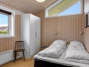 A bedroom with a bed, a chair, a wardrobe, and a small table. - "Ellanor" - 100m from the sea by Interhome (Broager)