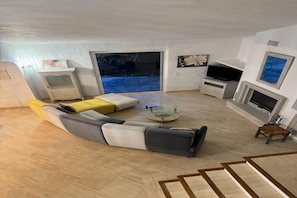 Ein modernes Wohnzimmer mit einem Ecksofa, einem Glastisch, einem Flachbildfernseher und einem Kamin.
