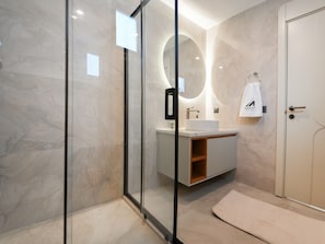 Ein modernes Badezimmer mit Duschkabine aus Glas, einem Waschtisch und einem Handtuch an der Wand.