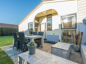 A patio area with a table and chairs, a potted plant, and a wooden bench. - Holiday Home in Renesse With Swimming Pool (Renesse)