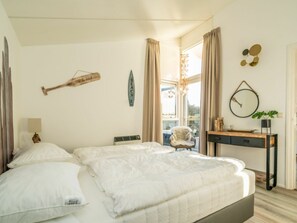 A bedroom with a bed, a desk, a chair, and a window with curtains. - Holiday Home in Renesse With Swimming Pool (Renesse)