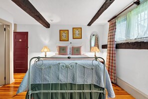 A bedroom with a bed, two bedside lamps, a red door, and a window with curtains. - Entire 1750 Inn + Event Barn + Concierge | Old Drovers Inn & Carriage House (Dover Plains)