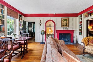 A traditional living room with a fireplace, bookshelves, and a dining area. - Entire 1750 Inn + Event Barn + Concierge | Old Drovers Inn & Carriage House (Dover Plains)