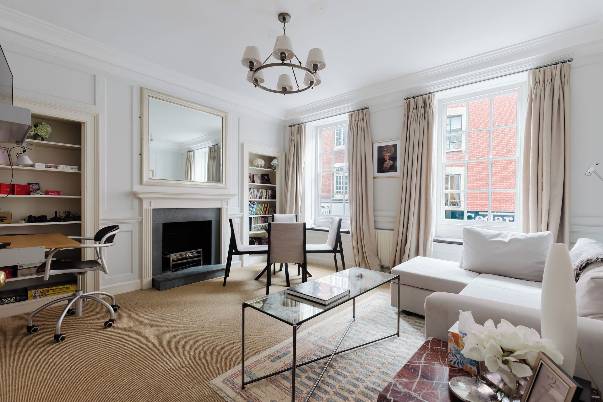 A well-lit living room with a fireplace, a sofa, a coffee table, and a bookshelf.