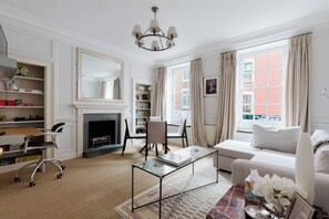 A well-lit living room with a fireplace, a sofa, a coffee table, and a bookshelf. - Classically Elegant 3BDR Soho Townhouse (London)