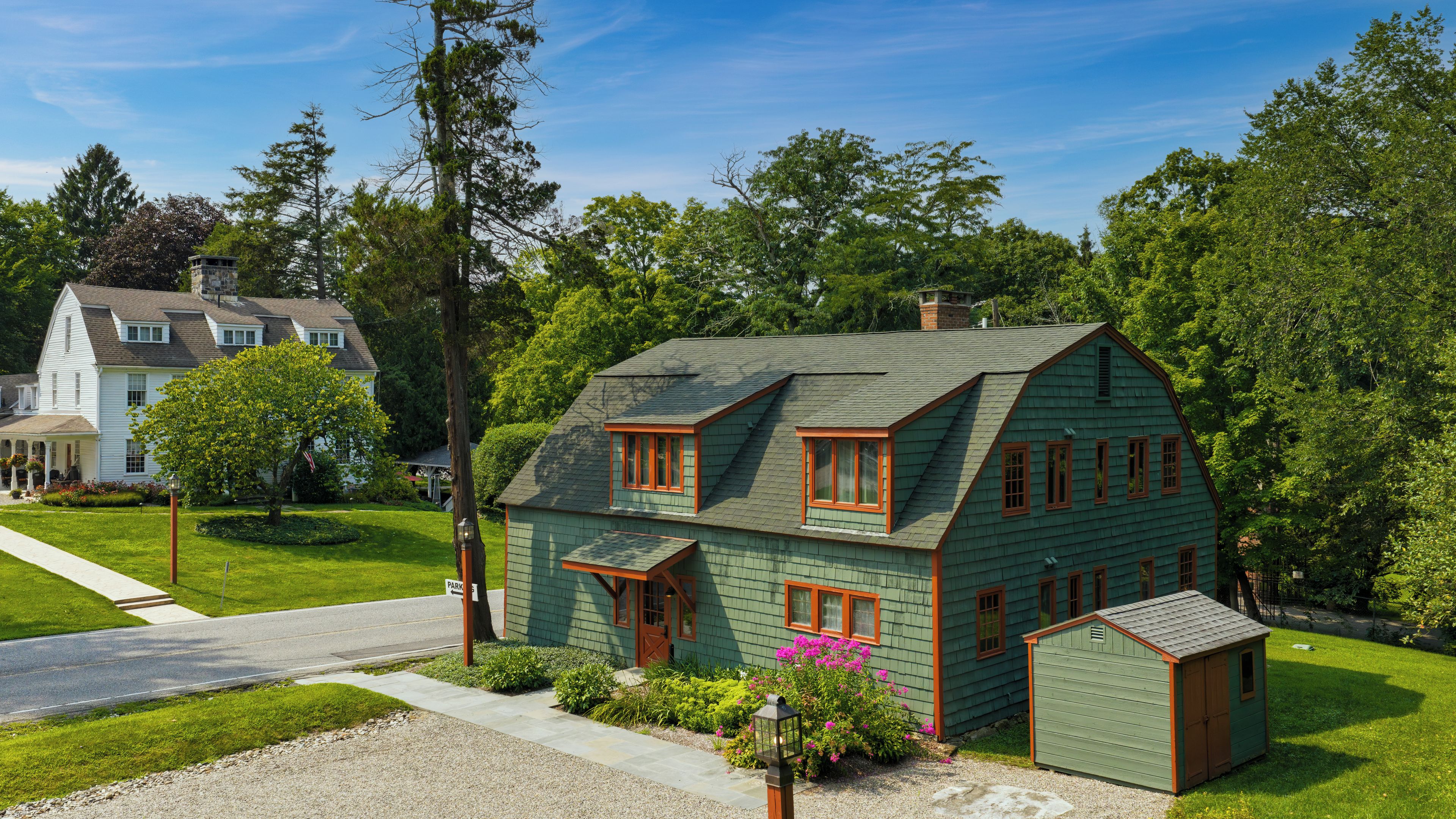 Ein zweistöckiges Haus mit grüner Fassade und einer kleinen angebauten Garage.