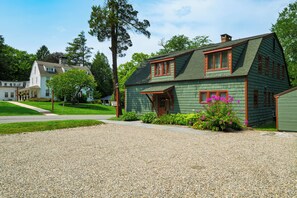 Une maison à deux étages avec une allée en gravier et un panneau indiquant « PARKING ».
