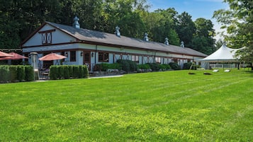 A building with a white facade and brown trim, surrounded by a well-maintained lawn and trees.