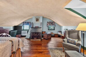 Ein gemütliches Dachzimmer mit Kamin, Holzboden und einer komfortablen Sitzecke.