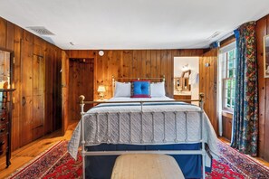 A wooden-paneled bedroom with a bed, a nightstand, a dresser, and a window with curtains. - Liz Taylor's 1962 Hideaway + Brass Queen | Near Appalachian Trail | The Gables 1 (Dover Plains)