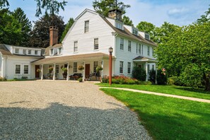A large white building with a covered porch and a gravel driveway. - Liz Taylor's 1962 Hideaway + Brass Queen | Near Appalachian Trail | The Gables 1 (Dover Plains)