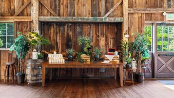A rustic wooden interior with a wooden table displaying various items, including mugs and plants.
