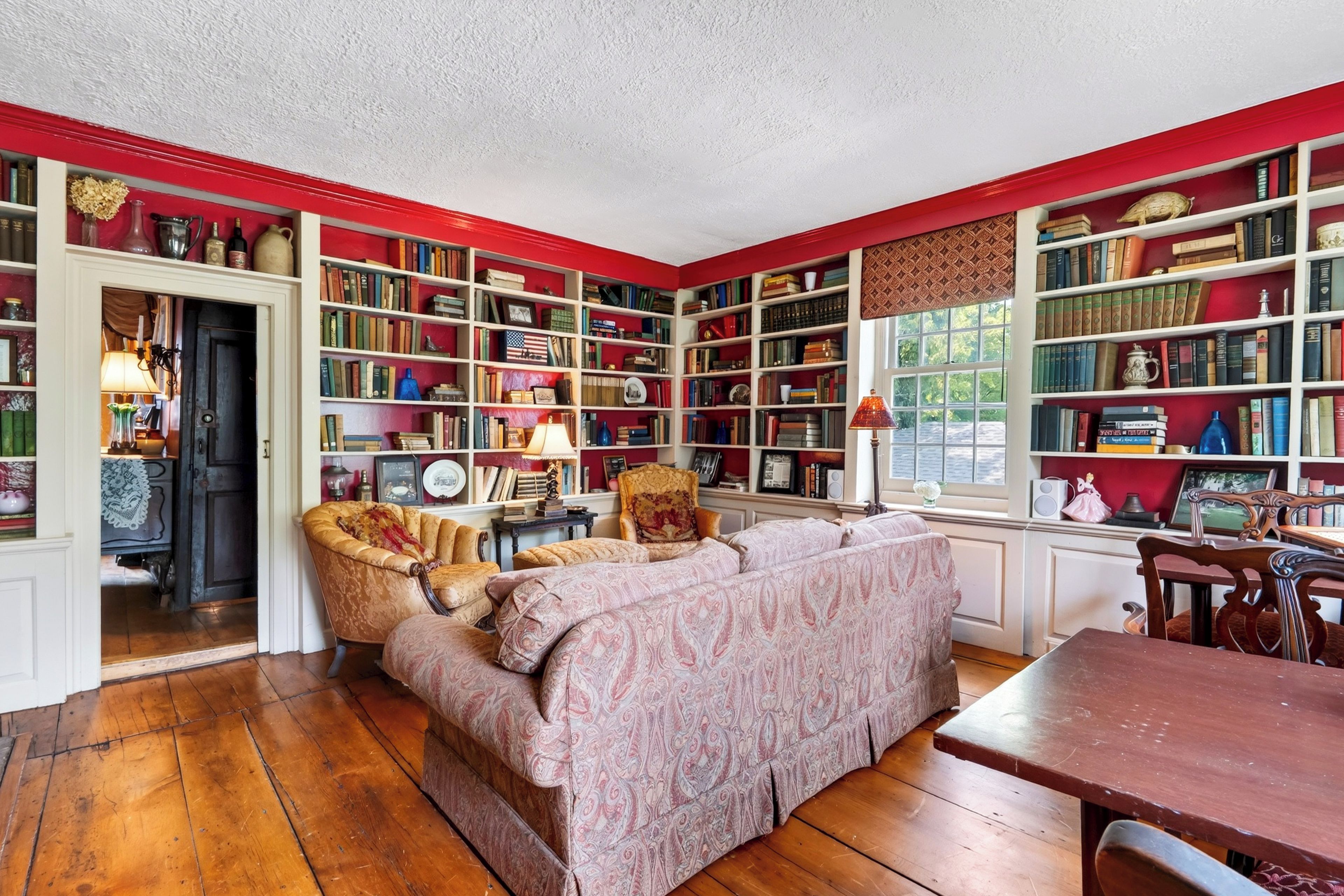 Eine Bibliothek mit Bücherregalen, einem Sofa und einem Esstisch.