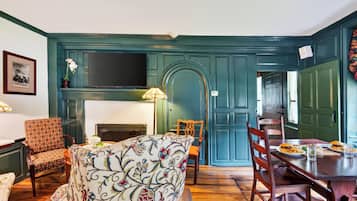 Una habitación con chimenea, una mesa de comedor con sillas y un televisor montado en la pared.