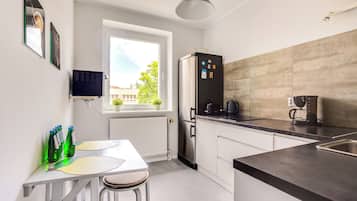 Una cocina moderna con refrigerador empotrado, ventana con vista a follaje y comedor con mesa y sillas.