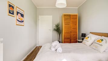 Un dormitorio con cama, armario, puerta y dos cuadros en la pared.