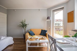 A modern living room with a sofa, a coffee table, and a potted plant. - Jasny Apartament blisko Starego Browaru (Poznań)