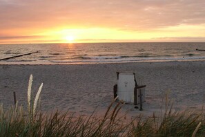 A beach with a lifeguard stand and waves at sunset. - Holiday home with 2 bedrooms (Ostseebad Prerow)