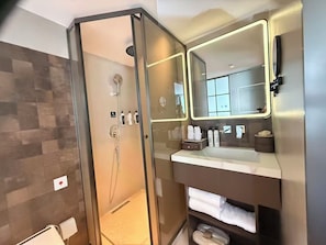 A modern bathroom with a glass-enclosed shower, a vanity with a mirror, and a towel rack. - Wanda Moments Resort Dali Ancient City (Dali)