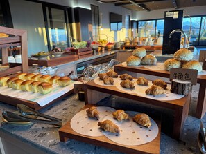 Mostrador de panadería con diversas opciones de panadería, incluyendo bollos y croissants, sobre tablas de madera.