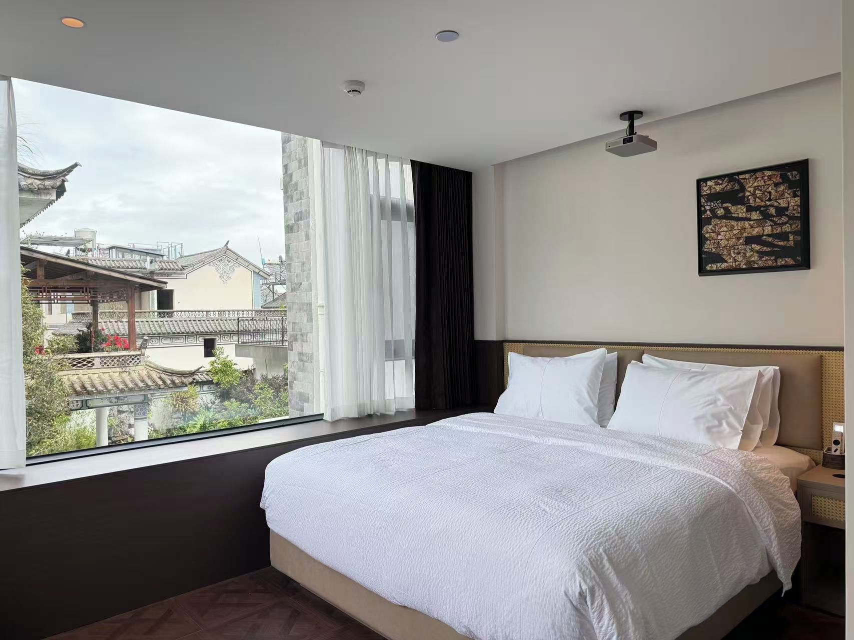 A hotel room with a large bed, a view of traditional architecture outside, and a ceiling fan.