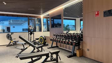 Une salle de sport équipée de matériel d’exercice, d’un porte-haltères et de grandes fenêtres offrant une vue dégagée.