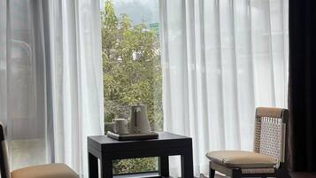 Una habitación con vistas, cortinas translúcidas, una mesita con bandeja y dos sillas.