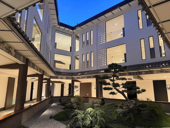 A multi-level building with large windows and a landscaped garden area.