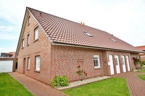 A single-story brick house with a sloped roof, a small front porch, and a well-maintained lawn. - Holiday apartment with 2 bedrooms (Norddeich)
