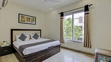 A hotel room with a bed, a nightstand, a window with curtains, a ceiling fan, and a framed picture on the wall.