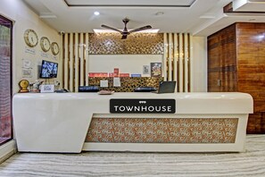 Un mostrador de recepción con un cartel que dice 'TOWNHOUSE' y un ventilador de techo arriba.