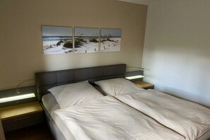 A bedroom with a bed, bedside tables, and wall art. - House at the dike 12c (Varel\/Dangast)