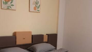 A bedroom with a bed, headboard, and two wall-mounted artworks.