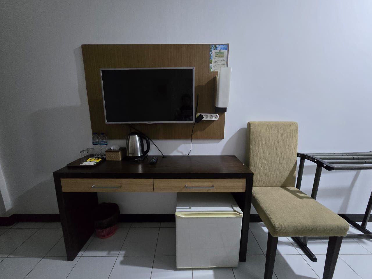 A room with a desk, chair, and a small refrigerator.