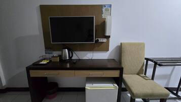 A room with a desk, chair, and a small refrigerator.