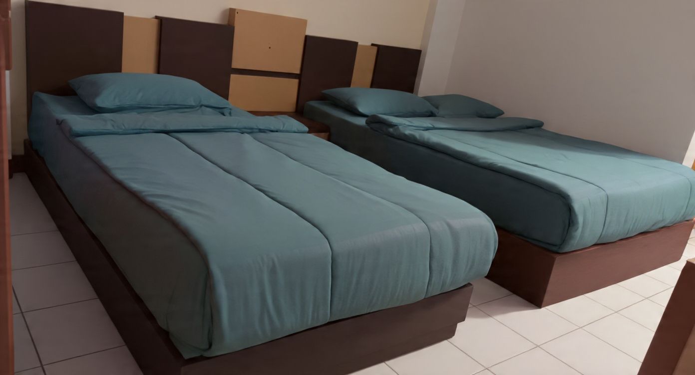 Two single beds with wooden headboards and matching blue bedding.