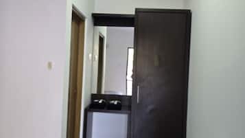 Una habitación pequeña con cama, un escritorio, un armario y un equipo de aire acondicionado.