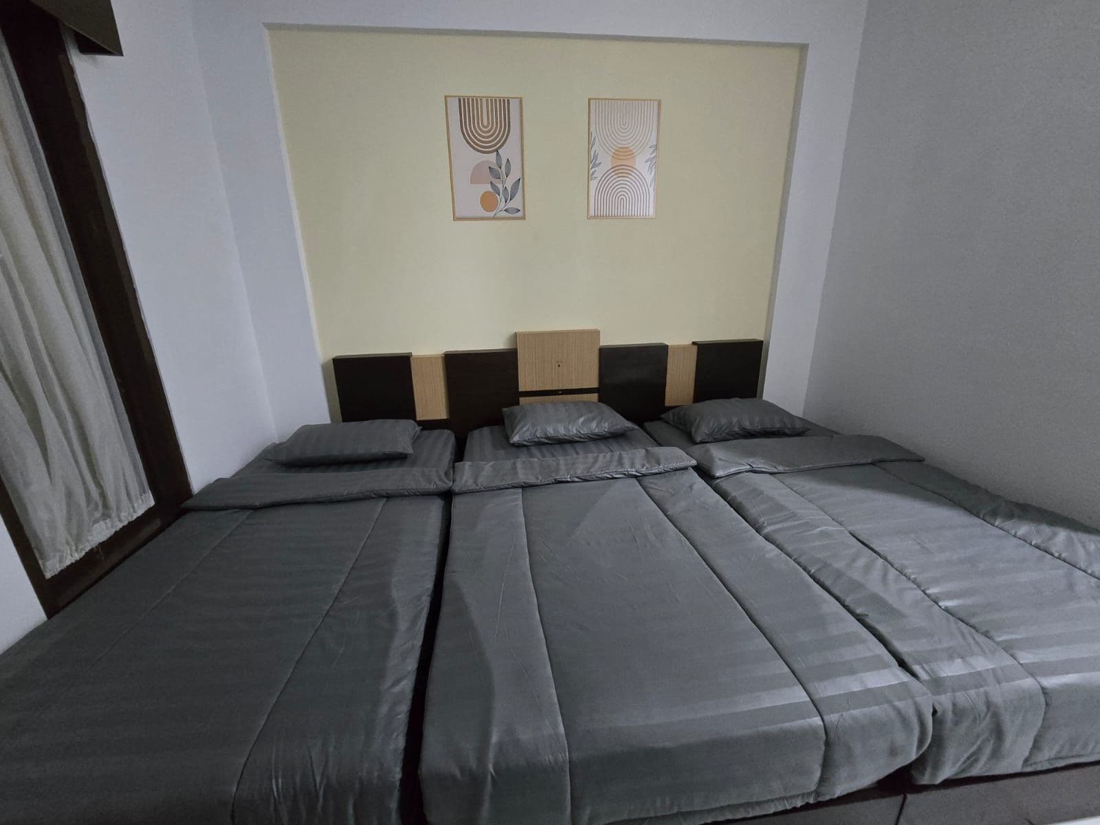 Una habitación con una cama grande, un cabecero de madera y dos obras de arte colgadas en la pared.