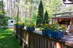 A wooden deck with flower planters, a small shed, and a building with a visible interior. - Holiday home in Dargow with swimming pool (Dargow)