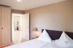 A hotel room with a bed, a nightstand, a lamp, and a wardrobe. - Holiday apartment with 1 bedroom (Timmendorfer Strand)