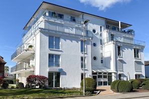 A multi-story hotel with balconies, a clear sky, and well-maintained landscaping. - Holiday apartment with 1 bedroom (Timmendorfer Strand)