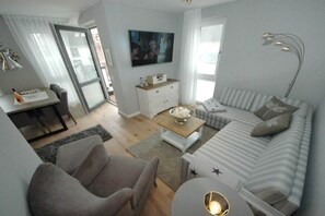A modern living room with a sofa, armchairs, a coffee table, and a television. - Sunset - OG/DG || Sylt (Sylt)