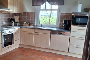A kitchen with a stove, oven, sink, and a window with a view of the outdoors. - Farmhouse-marsh view (Poppenbüll)