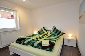 Een slaapkamer met een bed, nachtkastjes, een raam en een radiator.