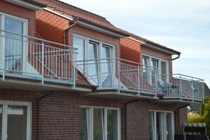 A residential building with multiple balconies, brick facade, and windows. - Holiday apartment with 1 bedroom (Norddeich)
