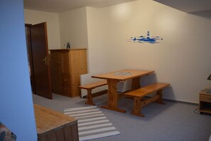 A room with a wooden table and benches, a cabinet, a radiator, and a wall with a lighthouse mural. - Holiday apartment with 3 bedrooms (Schillig)