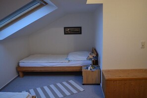 A small, single-bed room with a sloped ceiling, a bedside table, a nightstand, a small rug, and a framed picture on the wall. - Holiday apartment with 3 bedrooms (Schillig)